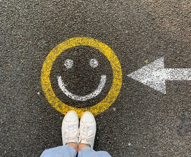 Road marking with a smiling face and arrow, representing a positive direction